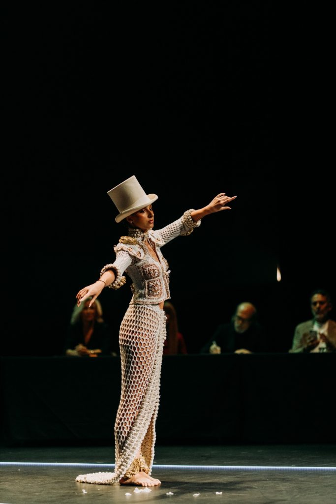 Sin Raíves no hay Futuro. Mujer bailando en el escenario, vistiendo un traje elegante y un sombrero de copa.